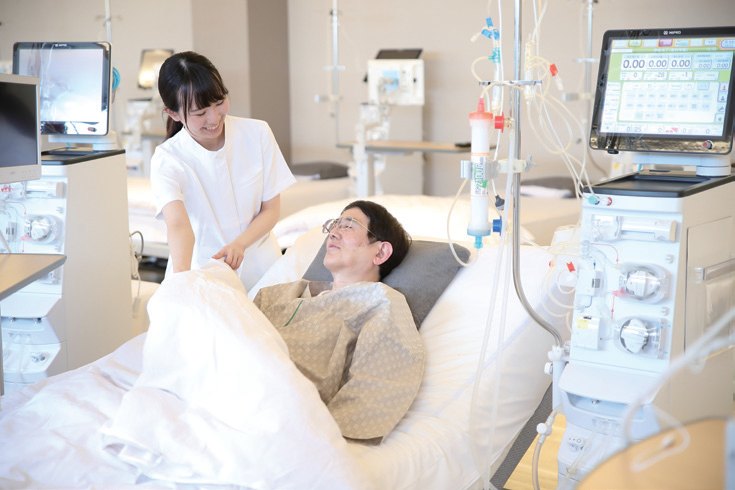 看護師が、ベッドで透析中の方に毛布をかけている