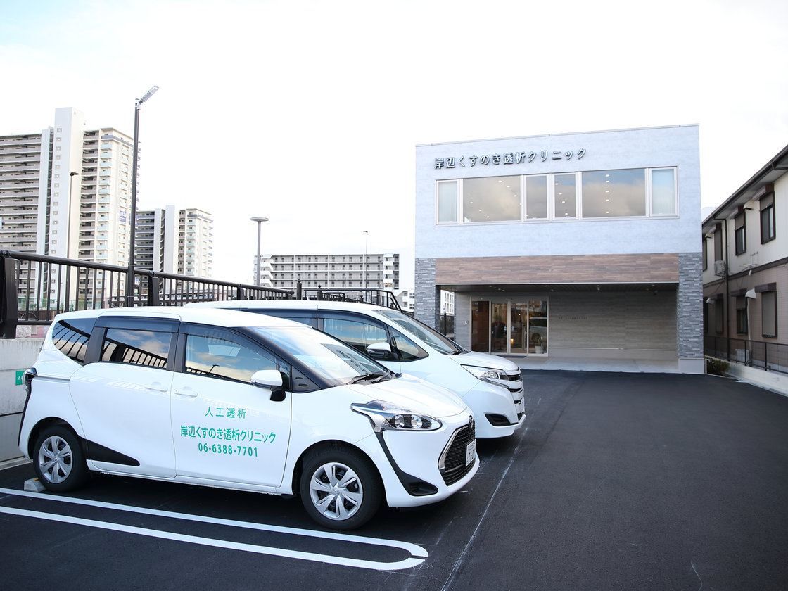 クリニックの建物の前にとまる白い送迎車2台